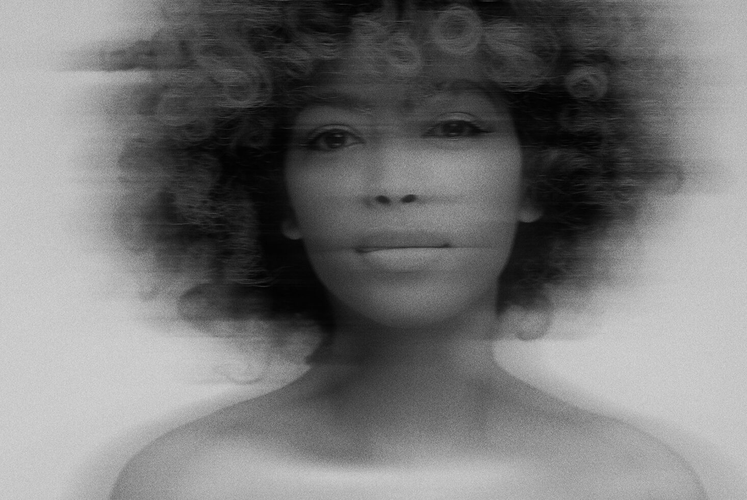 Monochrome portrait image of a person with curly hair in abstract motion blur style; ideal for designers seeking unique graphics or photo effects.