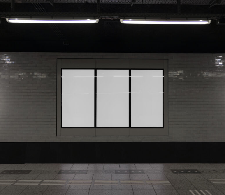 Three blank poster frames in storefront window with fluorescent ceiling lights
