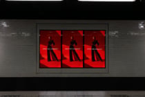 Red fashion billboard display with three identical screens in modern transit tunnel