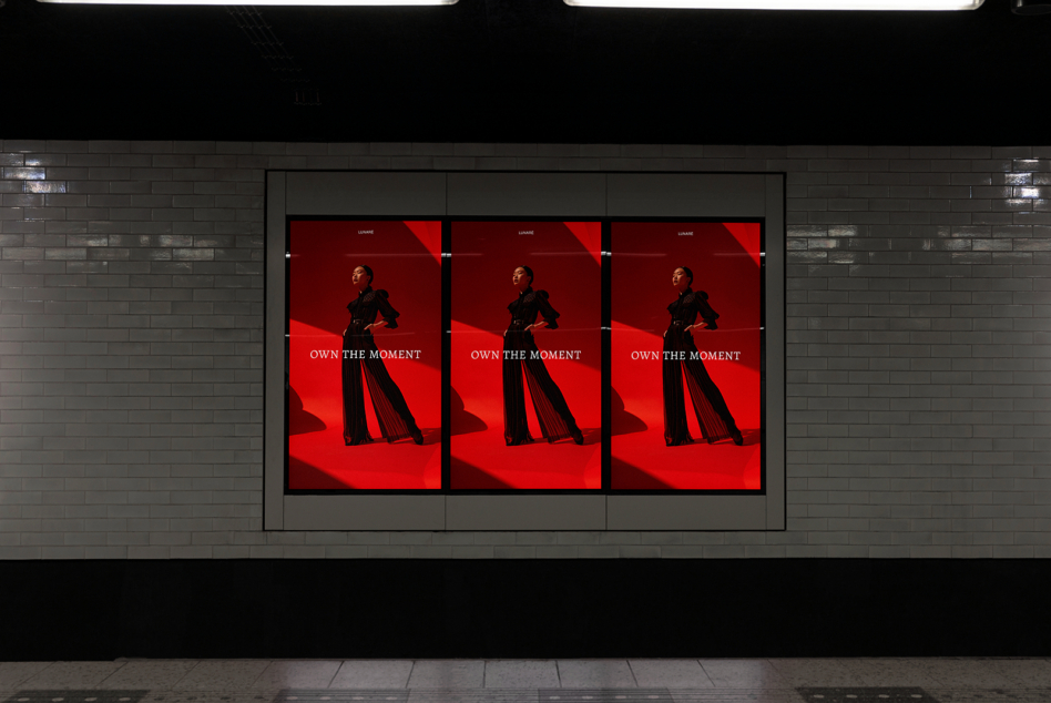 Red fashion billboard display with three identical screens in modern transit tunnel