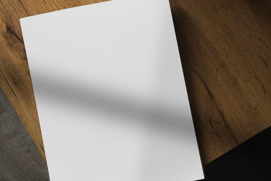 Blank white paper on wooden surface with soft shadow overlay