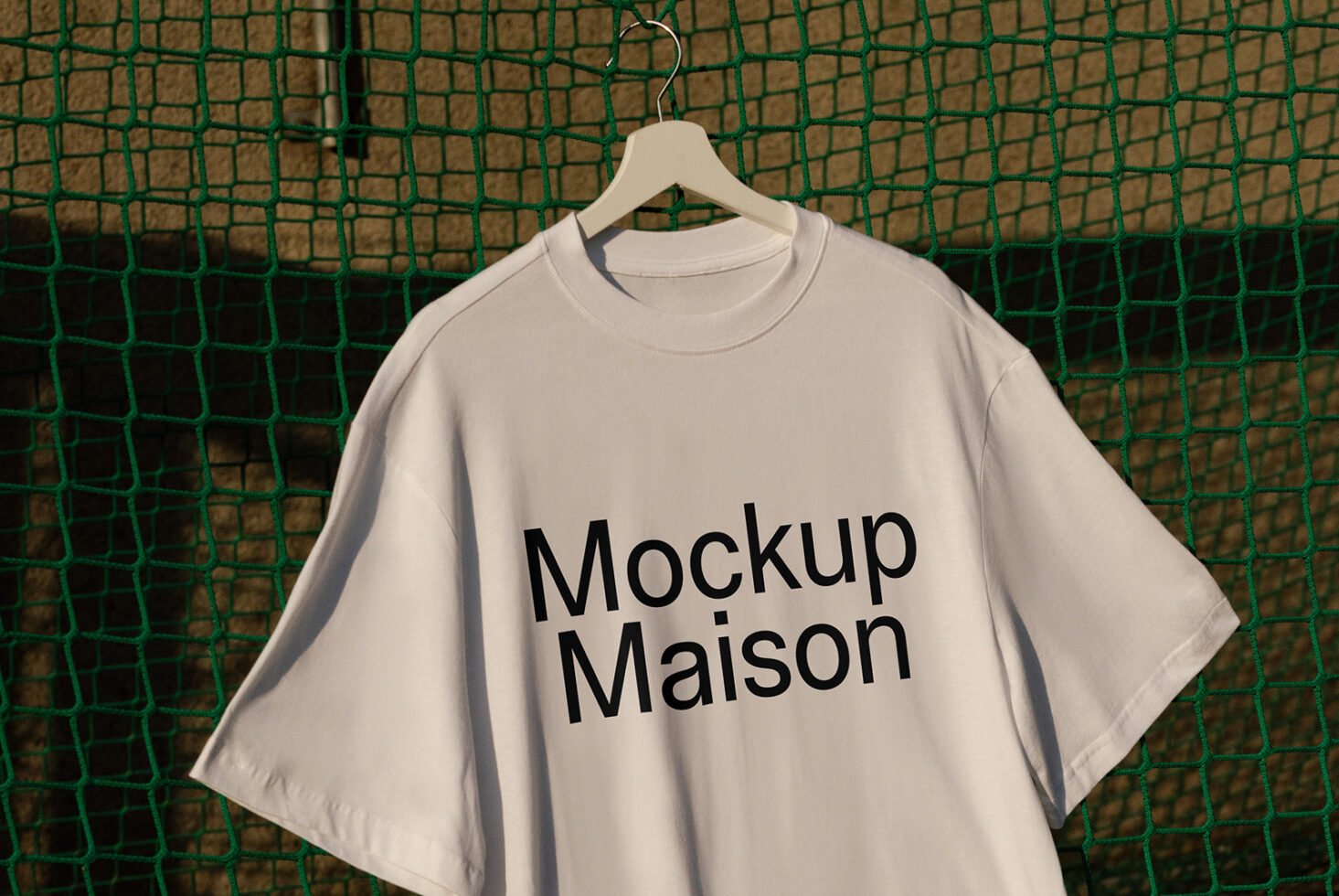 White T-shirt mockup hanging on a green net background perfect for showcasing logo design apparel mockups or template presentations for designers.