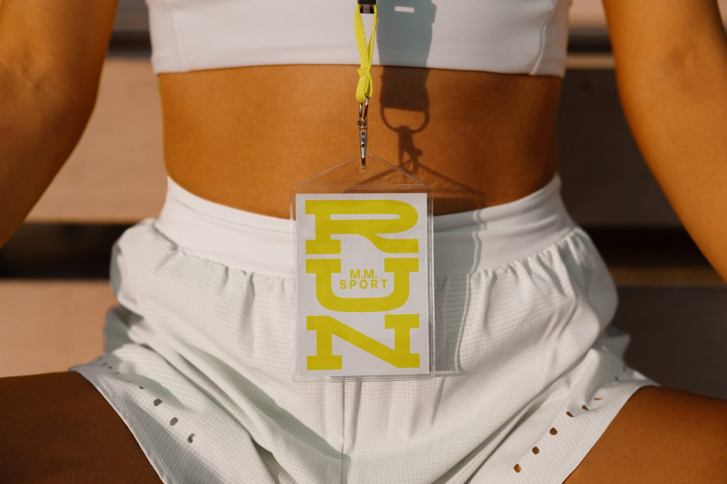 Athletic mockup featuring close-up of a person wearing white sports attire with a yellow RUN sport logo. Ideal for fitness branding, marketing designs.