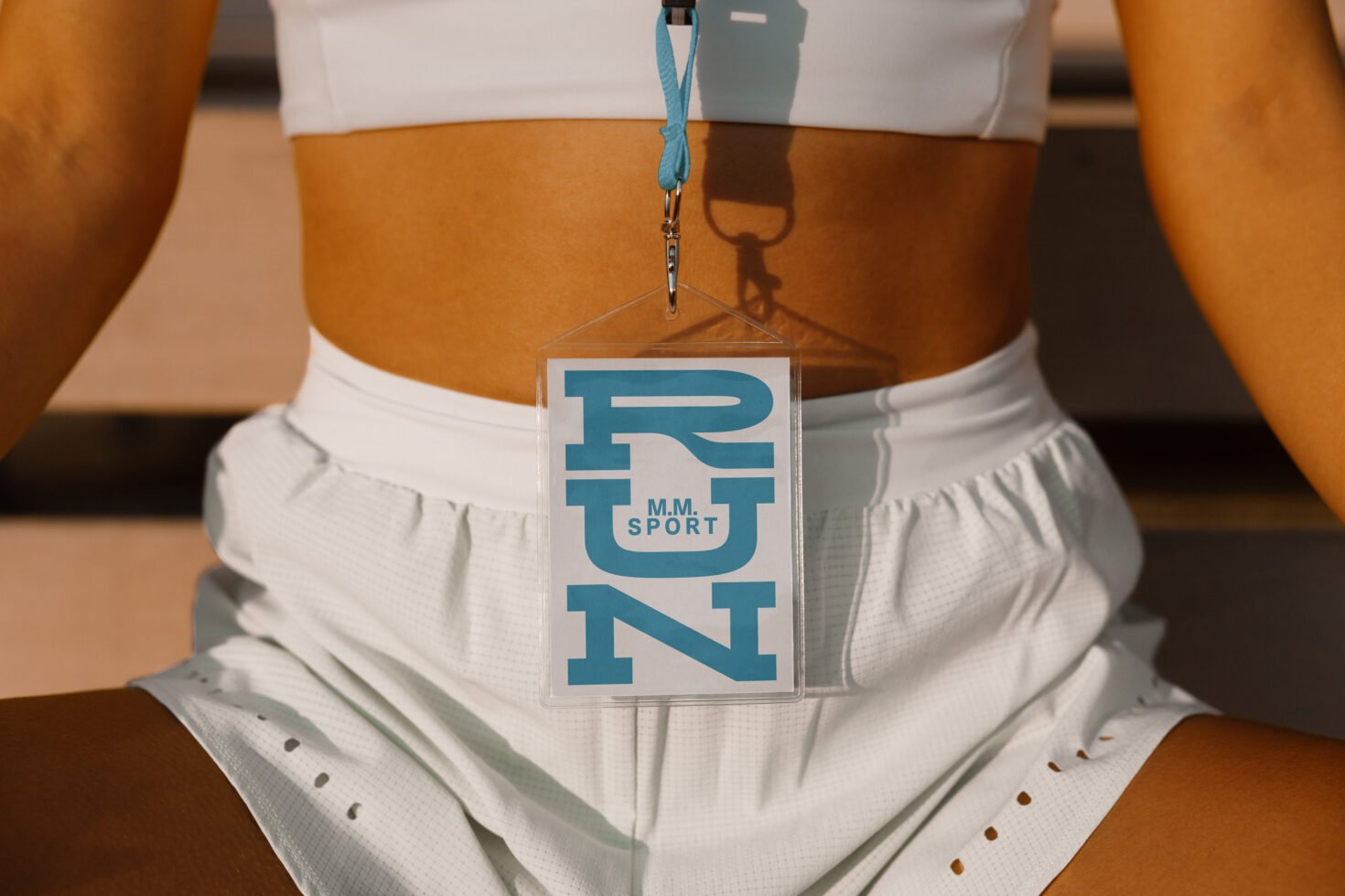 Athletic wear with a RUN badge hanging from a teal lanyard; perfect for sports-themed mockups and branding. White shorts sport top.