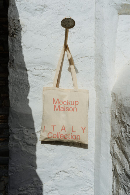 Natural canvas tote with coral text hanging on white brick wall