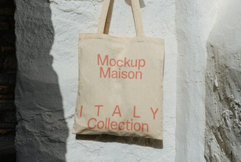 Cream colored tote with coral text displayed against white textured wall