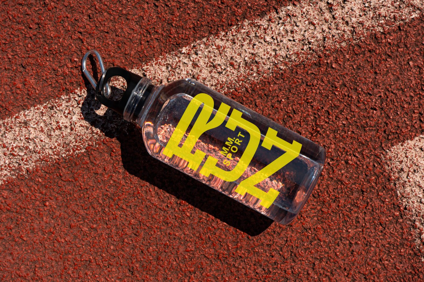 Clear water bottle mockup on textured red track surface ideal for design presentations with bold yellow text outdoor sports bottle product mockup designers