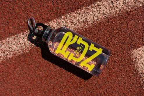 Clear water bottle mockup on textured red track surface ideal for design presentations with bold yellow text outdoor sports bottle product mockup designers