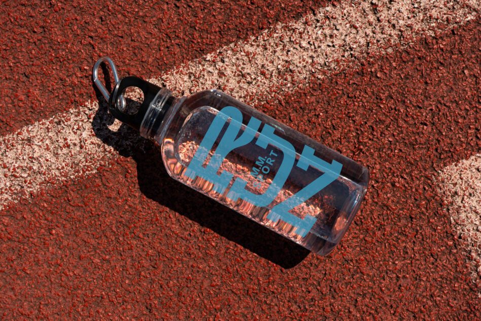 Clear water bottle with blue label on red clay tennis court