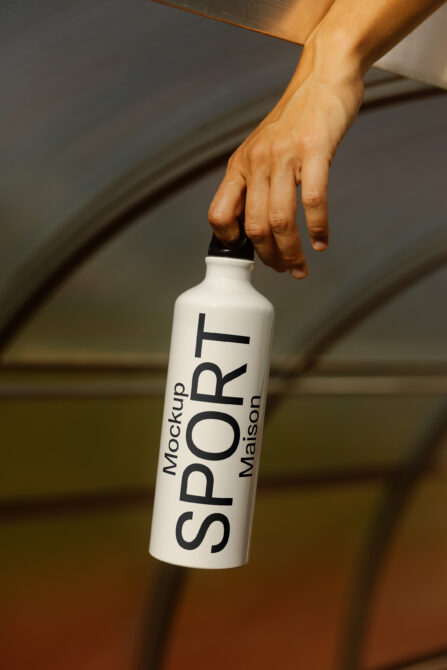 Hand holding white aluminum bottle with vertical text mockup