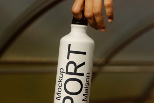 Hand holding a white bottle displaying sport theme mockup text. Ideal for designers looking for product mockup assets. Bottle design template.