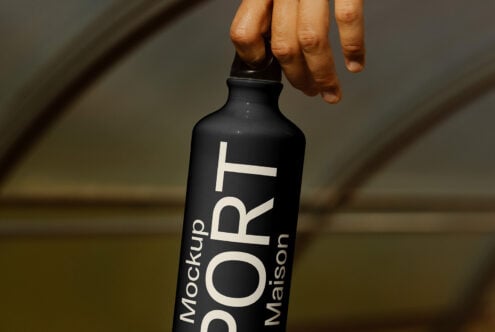 Hand holds a black water bottle with sport design text. Ideal for product mockups, beverage branding, and graphic design projects.