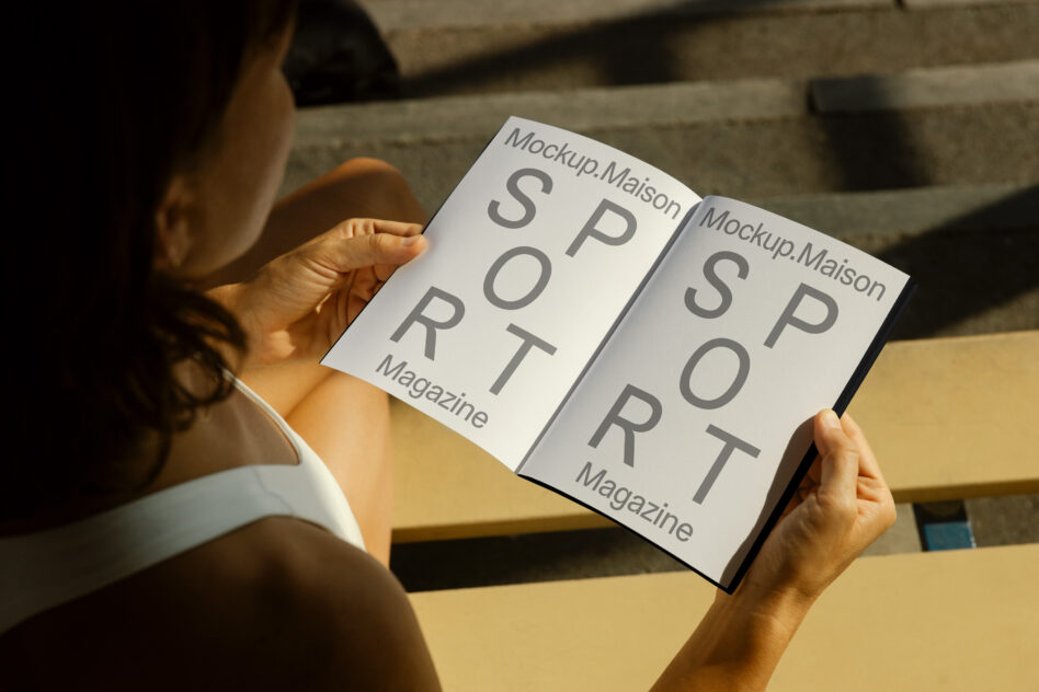 Person's hands holding open magazine with split page layout showing overlapping text mockup