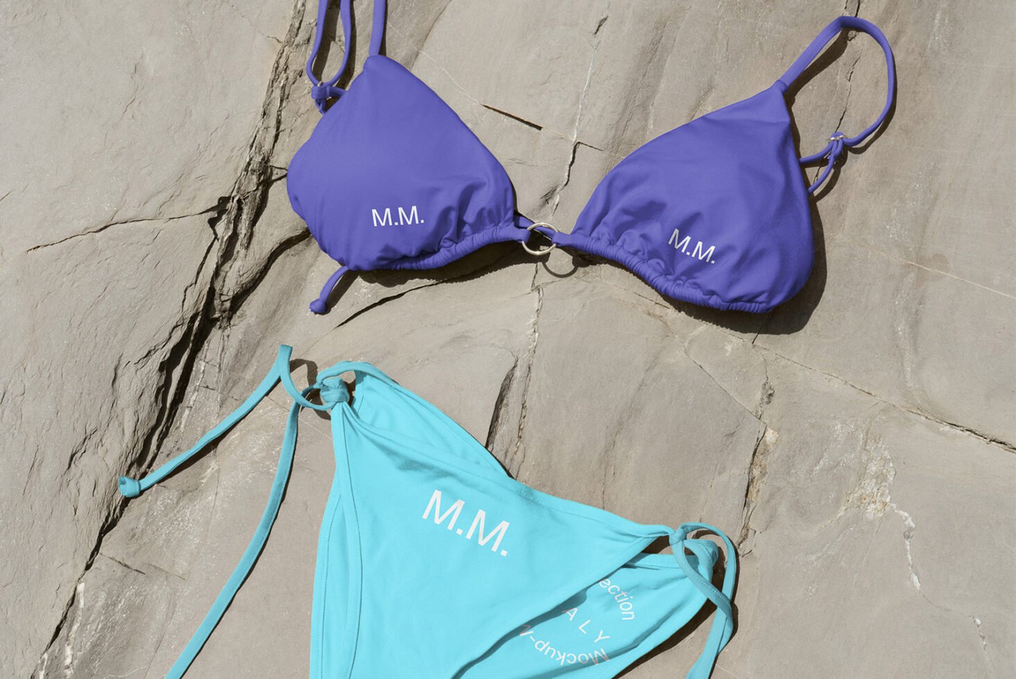 Colorful bikini mockup set on sandy rocks showcasing customizable design perfect for graphic designers fashion presentations or product templates.