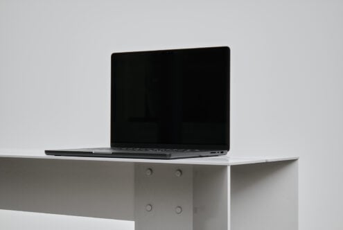 Sleek laptop mockup on minimal white table, ideal for showcasing digital graphics, UI designs, or website templates. Modern workspace inspiration.