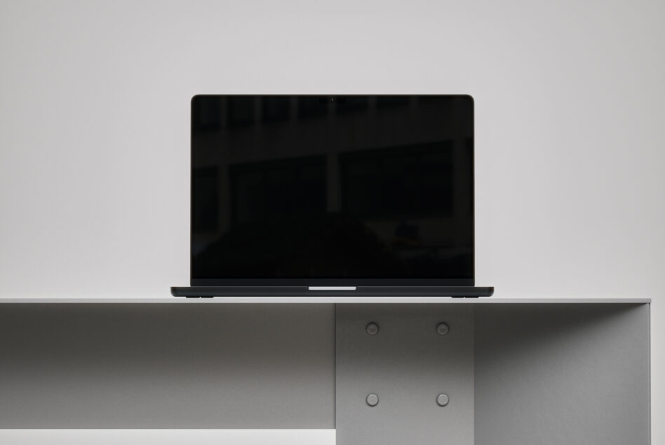 Laptop with black screen on shelf above storage cabinet with knobs