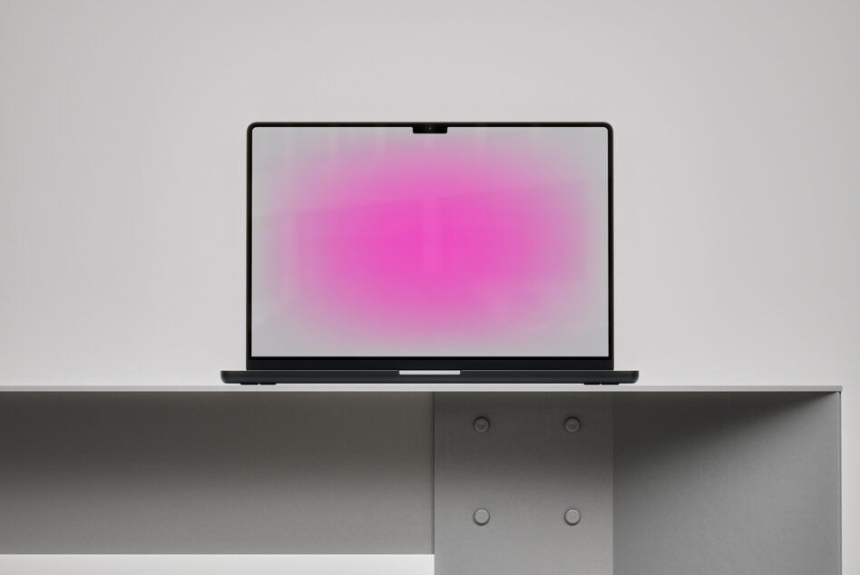 Laptop with pink gradient screen on shelf above storage cabinet
