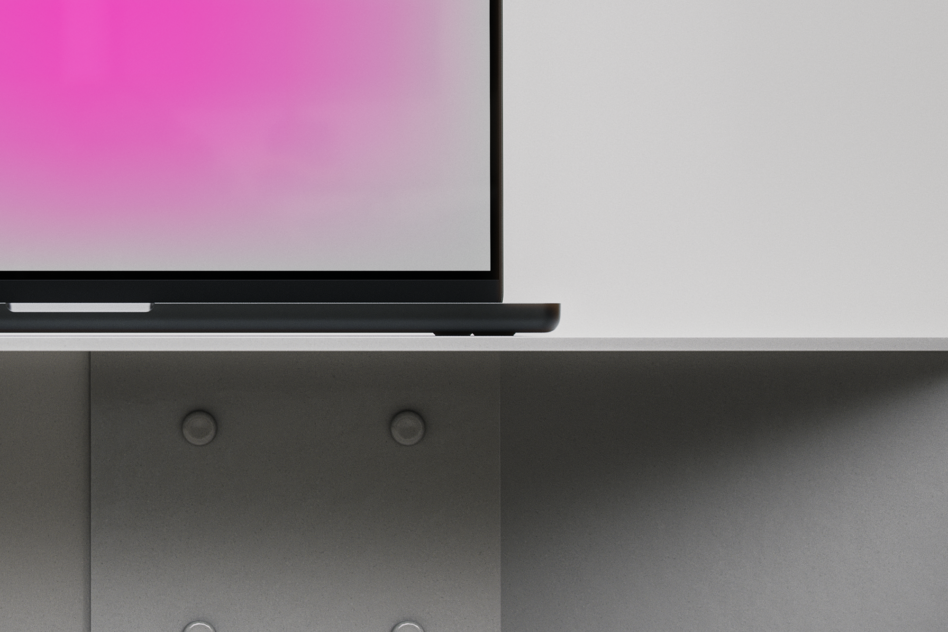 Laptop with pink gradient screen closed on desk, side angle view