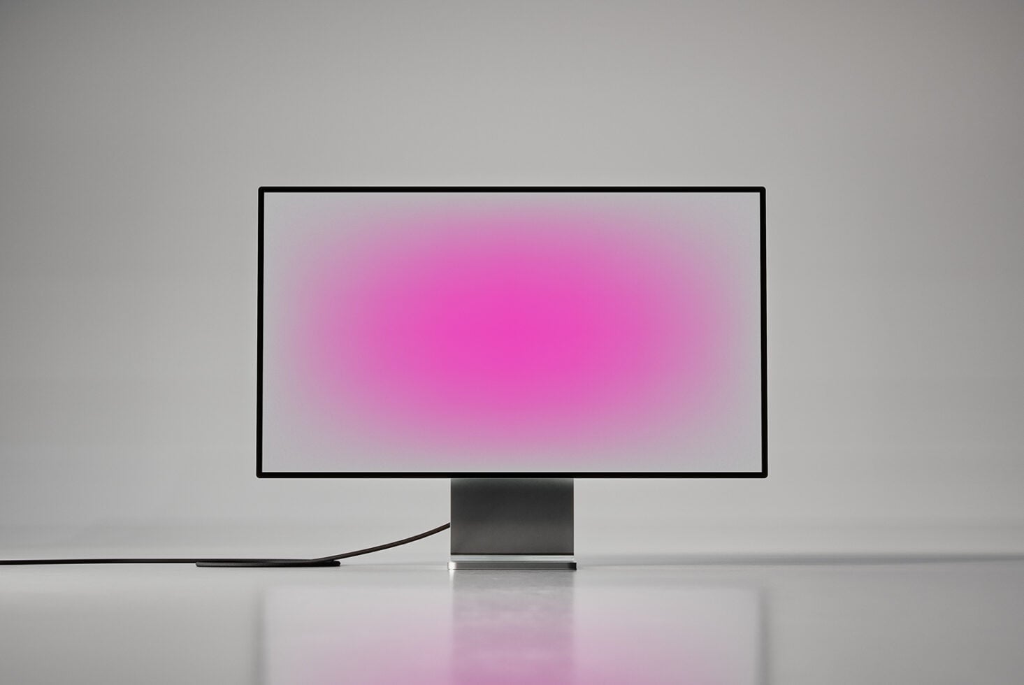 Desktop monitor with pink gradient display on gray pedestal stand