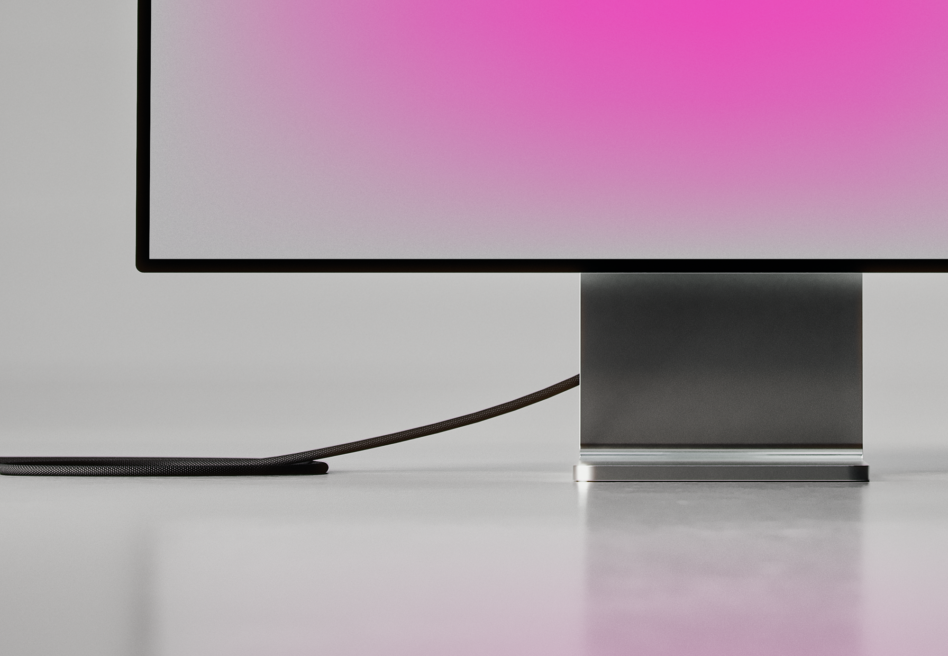Close-up of monitor showing pink gradient with black cable on white surface