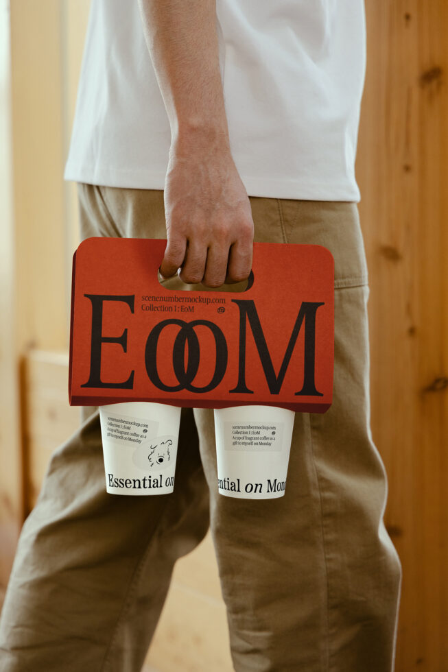 Person holding a red coffee cup carrier labeled EoM with two white cups Essentials on Monday. Mockup template for designers packaging branding SEO.