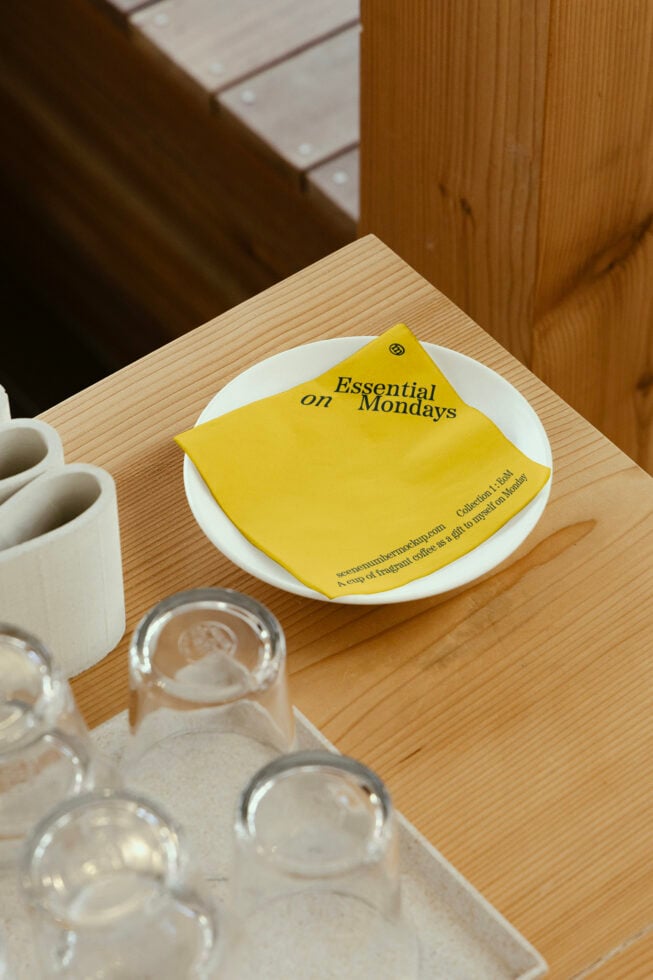Mustard yellow notecard mockup on white plate with coffee setup, bright sunlit workspace
