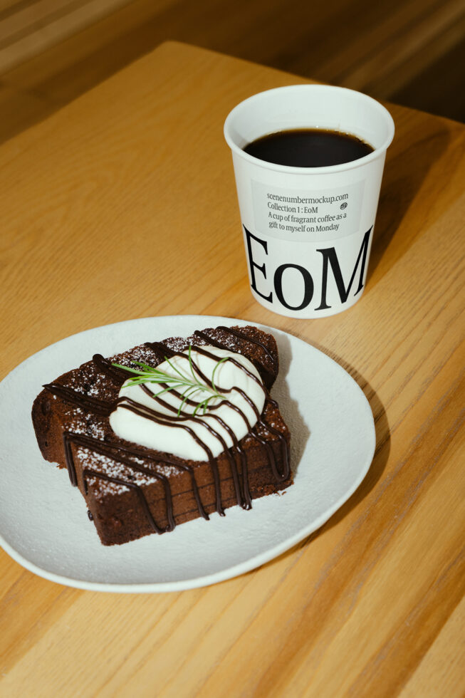Coffee cup mockup on wood table beside a chocolate cake. Ideal for designers seeking realistic food and beverage presentation templates and graphics.