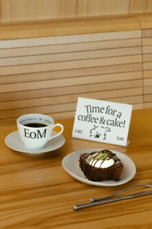 Cafe branding mockup with EoM cup, white table tent, chocolate cake on wooden table