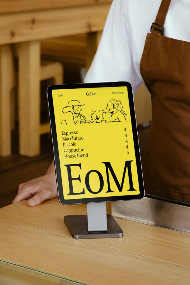 Tablet on cafe counter displays coffee menu in modern design. Keywords: mockup, template, coffee shop, menu, digital signage, tablet display, cafe decor.
