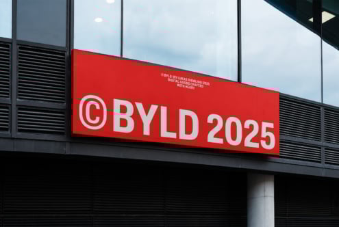 Red storefront sign with bold white text reading BYLD 2025. Modern font design ideal for mockups and branding templates. Urban display setting.