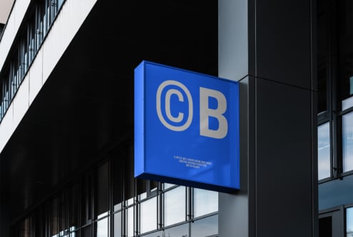 Blue logo sign with white letters CB on a modern building exterior. Ideal for branding, storefront, or signage mockup design. High-quality graphic resource.