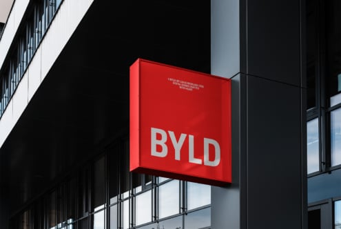 Red building sign reading BYLD in bold white letters mounted on a modern structure exterior. Perfect for branding, signage mockup, architectural design.