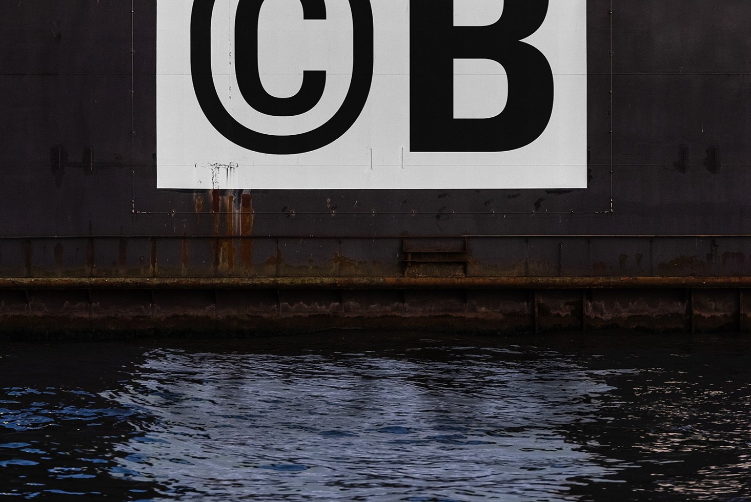 Industrial metal wall with bold black CB typography over water surface Digital asset for graphic designers Keywords typography industrial design