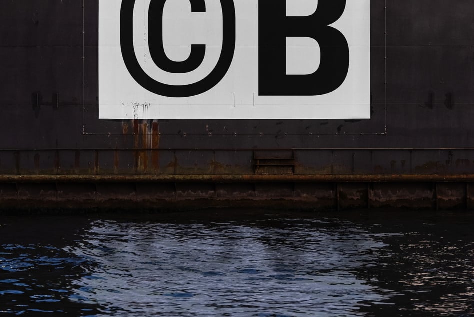 Close-up of industrial shipping sign showing large black CB letters with weathering