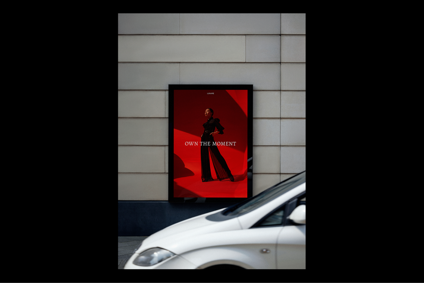 Street billboard mockup featuring a striking red fashion advertisement with the text own the moment. Ideal for showcasing modern design templates.