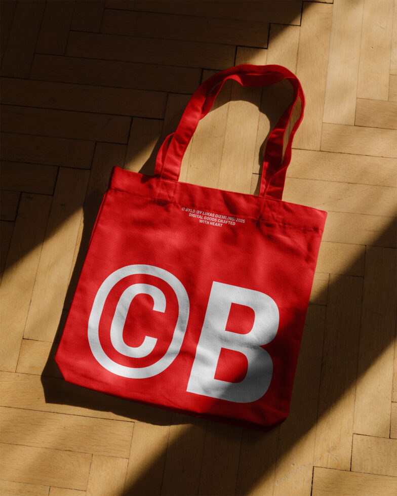 Red tote bag with bold white CB letters on wooden floor. Ideal for graphic design mockups, branding projects, and promotional materials for designers.