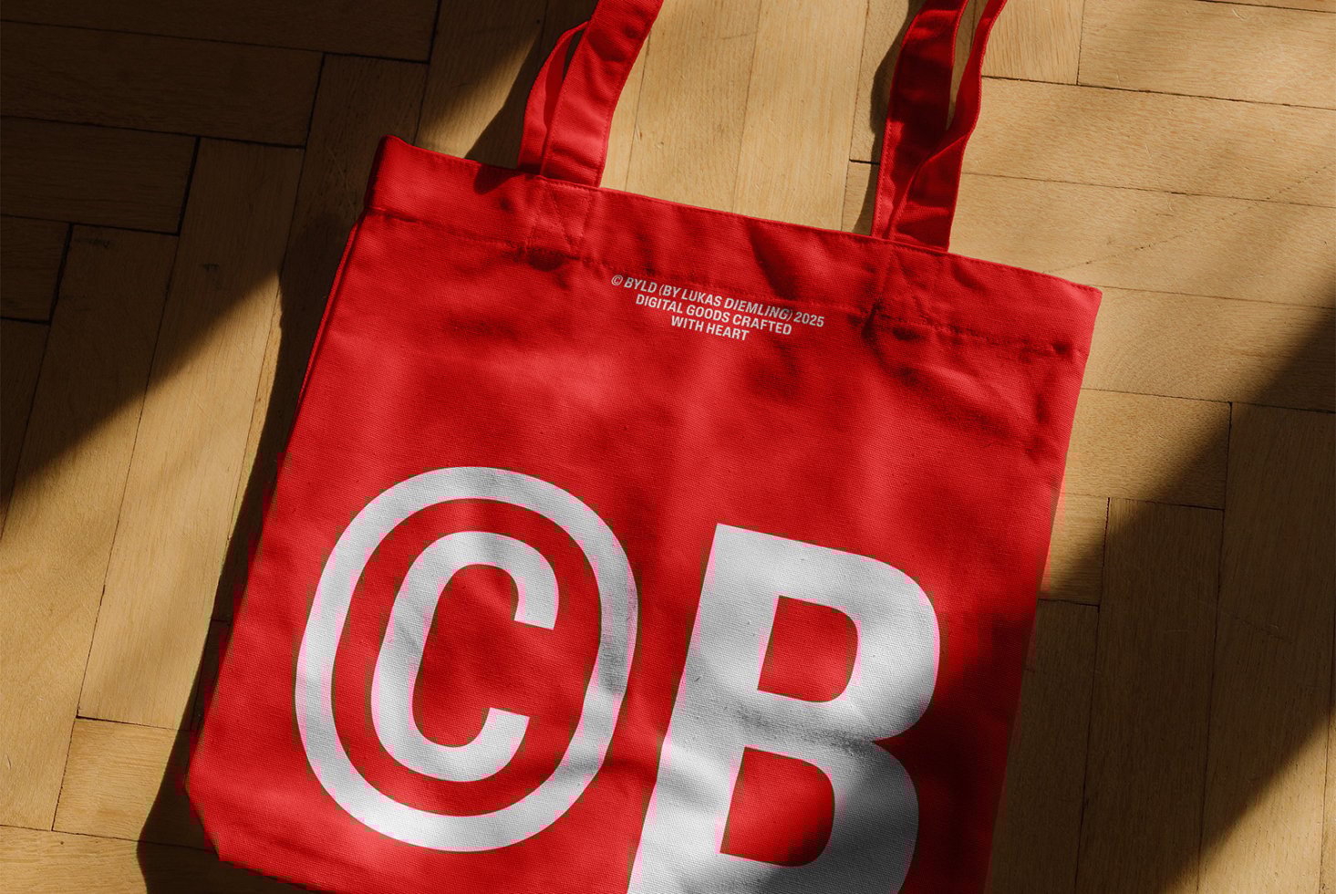Red tote bag mockup on wooden floor perfect for branding design. Features bold white CB lettering. Ideal for showcasing graphic designs or logos.