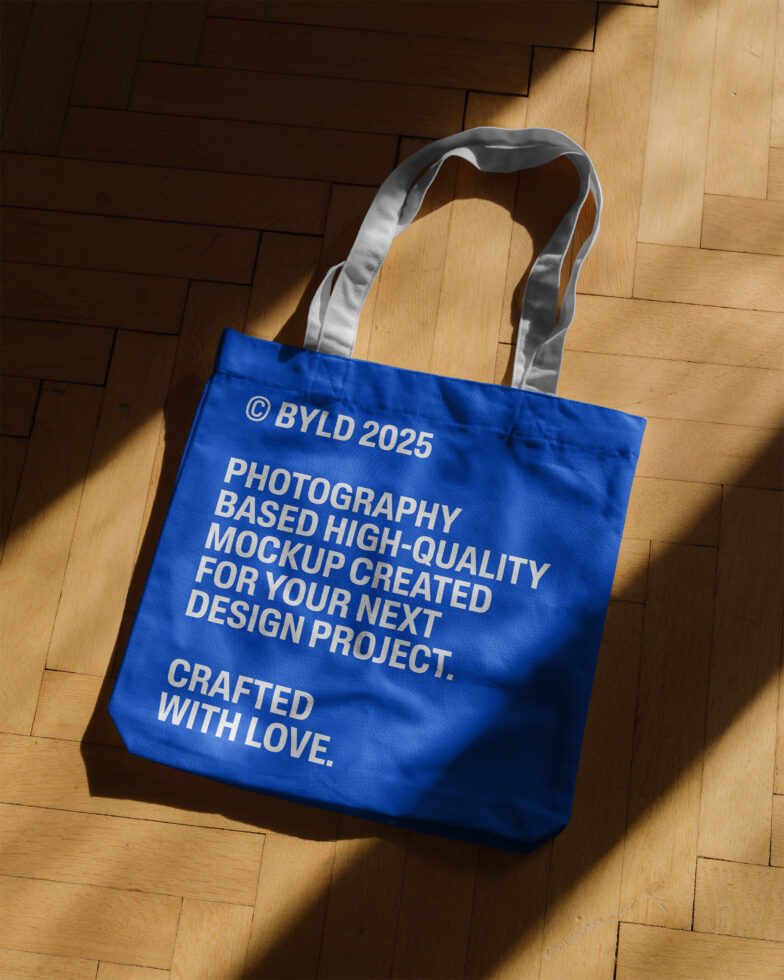 Blue tote bag mockup on wooden floor with text ideal for designers. High-quality merchandise display for creative projects. Perfect for templates.