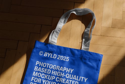 Cream colored tote with gray handles displaying partial logo on parquet