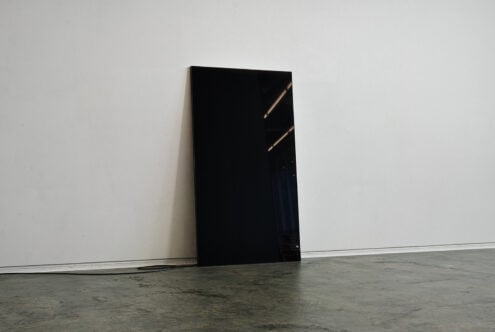 Minimalist mockup featuring a black screen leaning on a white wall suitable for showcasing graphics or templates in a modern design space.