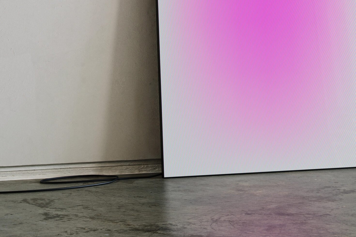 Minimalist mockup featuring a modern TV panel on a concrete floor with vibrant pink gradient display. Perfect for showcasing digital designs.