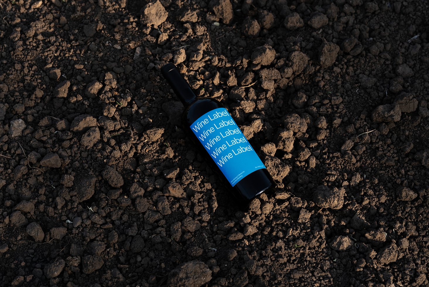 Wine label mockup on blue label bottle against earthy background ideal for designers looking for realistic product presentation or packaging design.