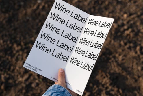 Wine label mockup with bold text on a folded page held outdoors. Perfect for branding and packaging design. Ideal for designers seeking templates.