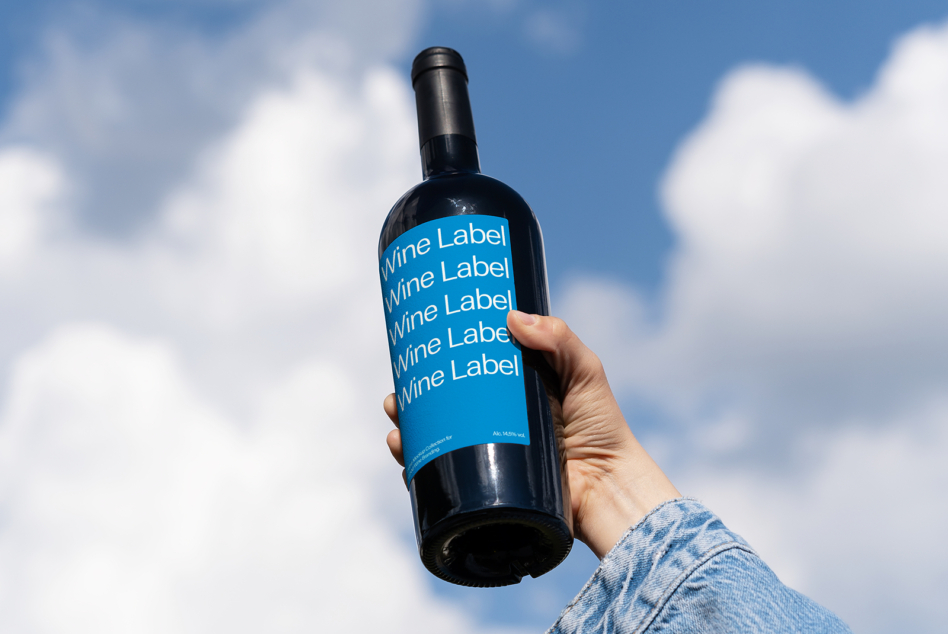 Wine bottle with bright blue label showing repeated text against blue sky