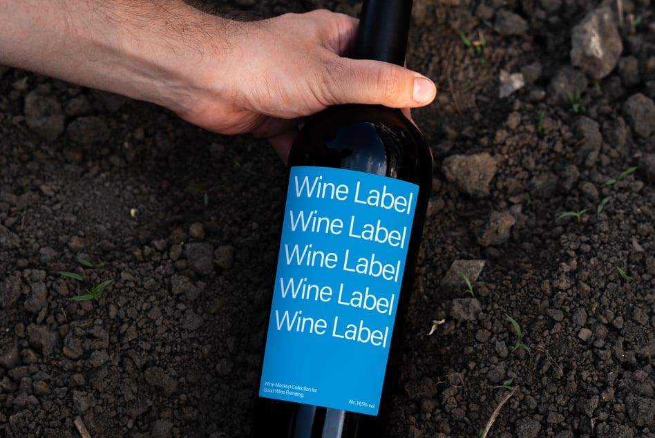 Wine bottle with bright blue label mockup on dirt ground close up