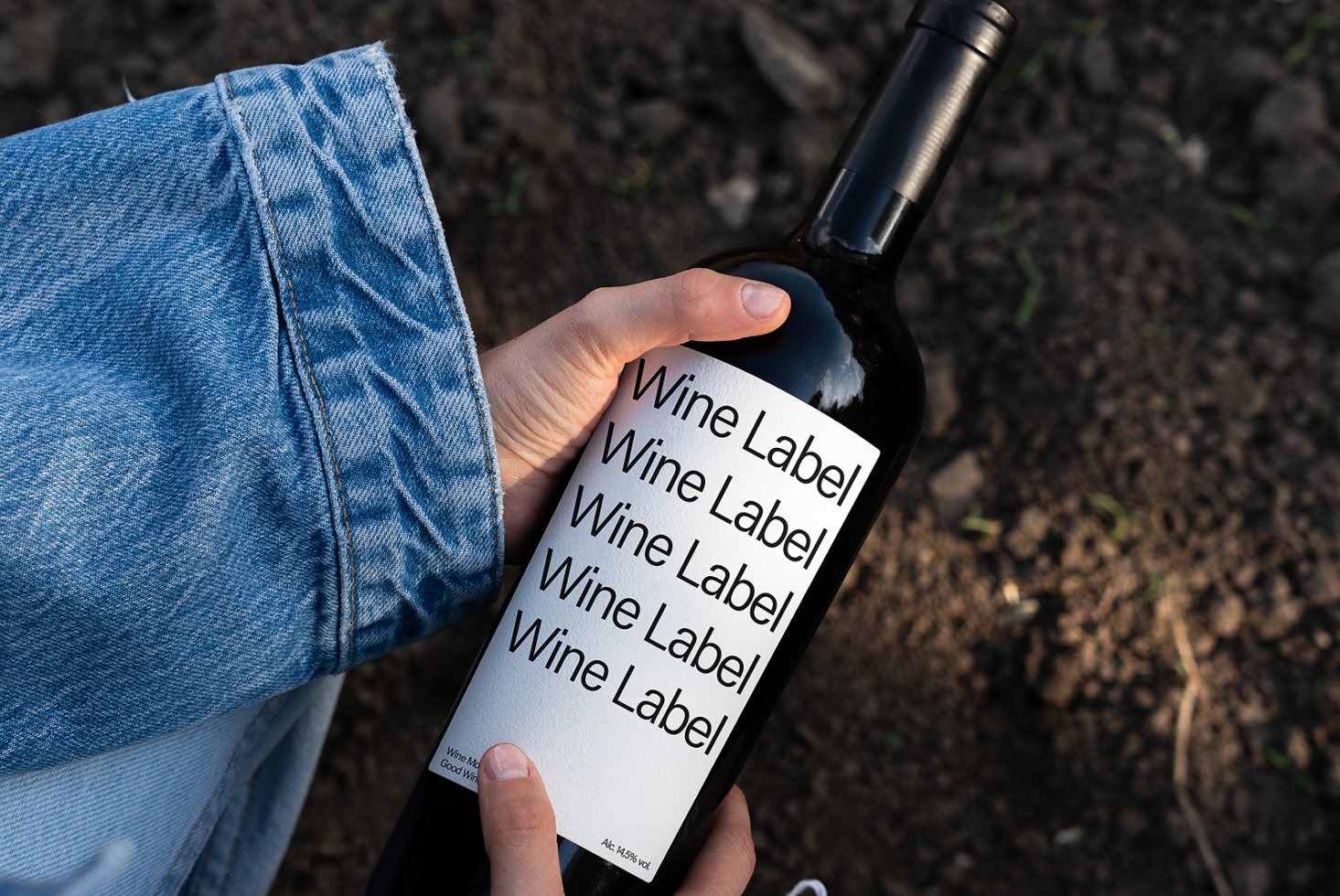 Hand holding wine bottle with minimalist mockup label design in an outdoor setting suitable for branding presentations and design projects.