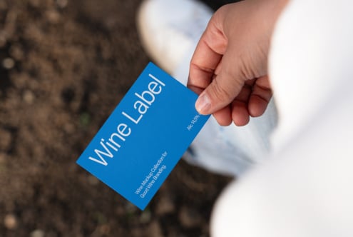 Close up of blue wine label mockup card being held outdoors