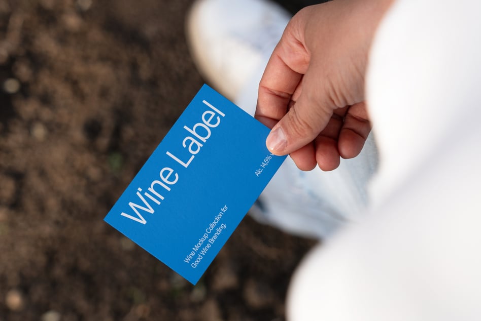 Close up of blue wine label mockup card being held outdoors