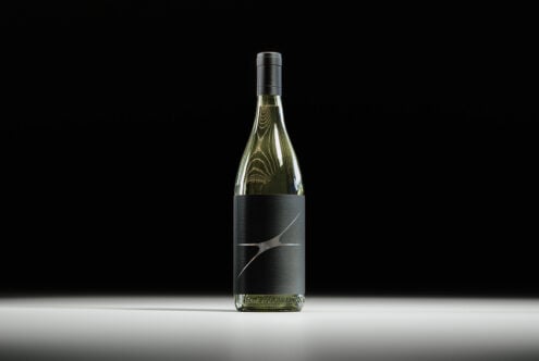 Elegant wine bottle mockup with a sleek black label design on a dark background ideal for branding projects and product presentations for designers.