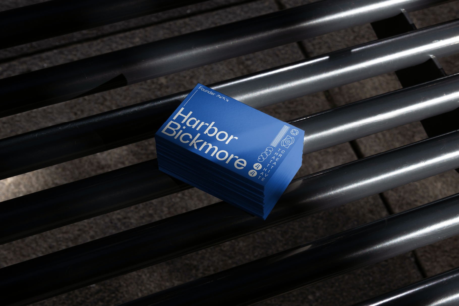 Blue business card for Harbor Bickmore stacked on industrial metal surface
